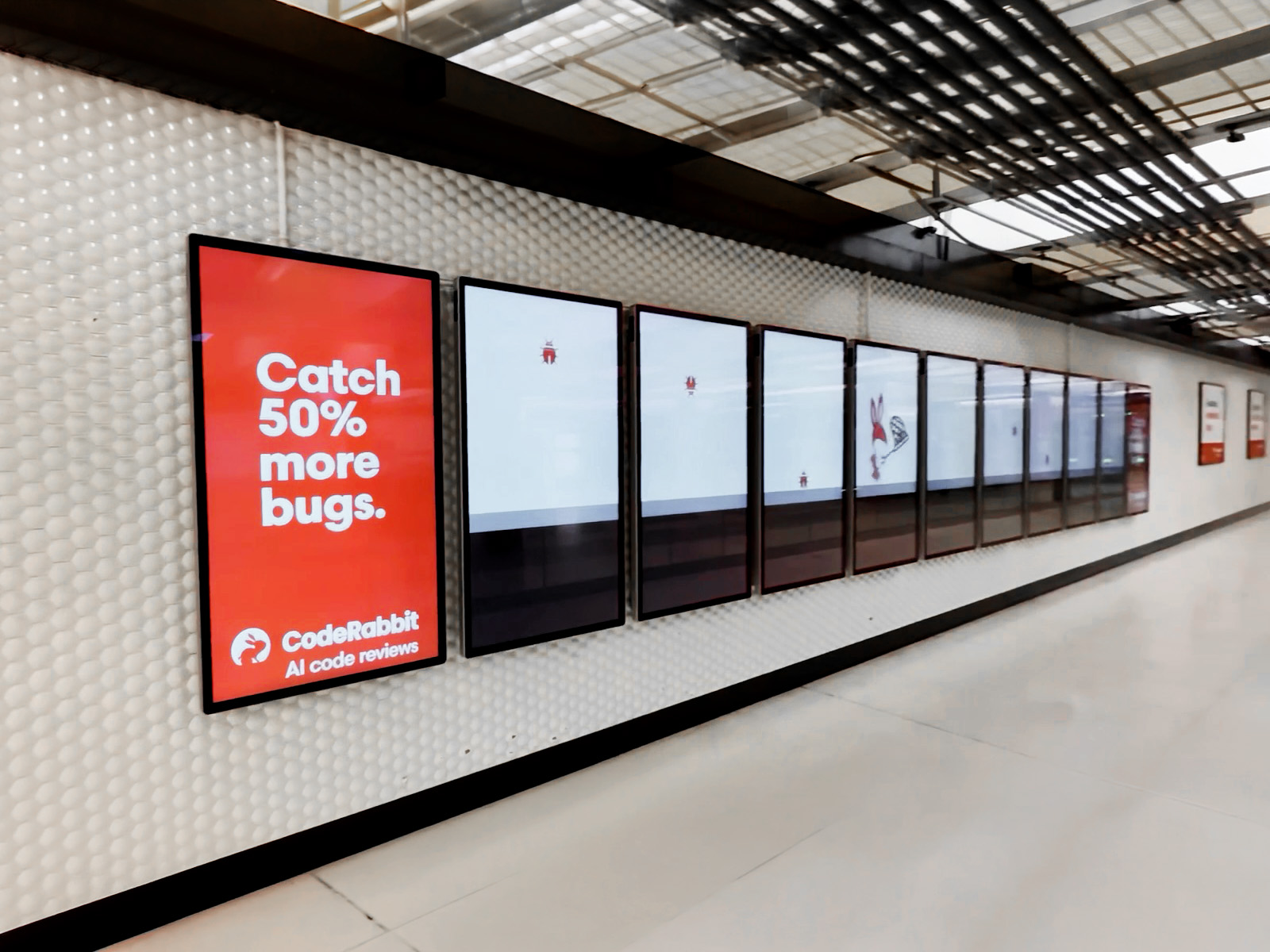 CodeRabbit campaign across a row of digital screens at a BART station, showing the rabbit mascot and Catch 50% more bugs message.